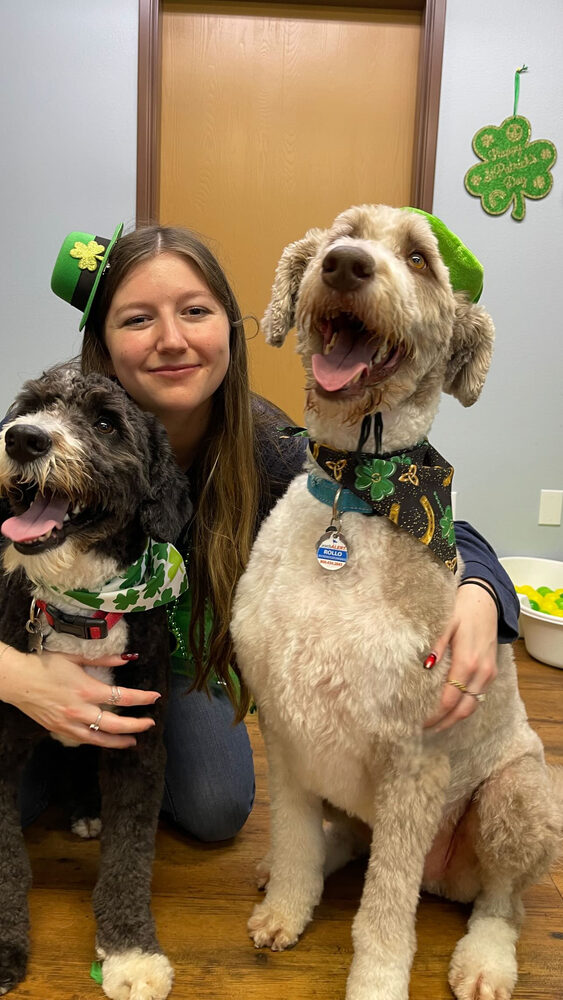 Haley with two doodle dogs dressed up for St. Patrick's Day