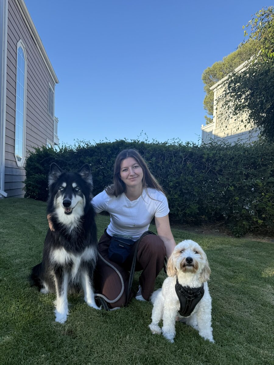 Haley kneeling in a backyard with a husky-mix and a cockapoo she trained
